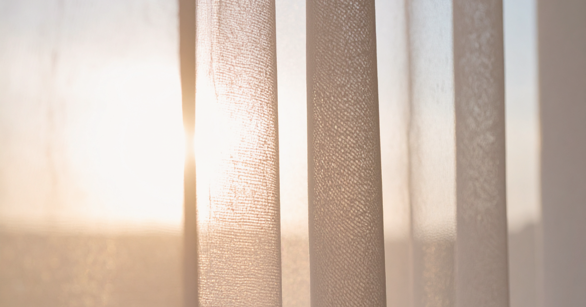 a view of the sun shining through the curtains